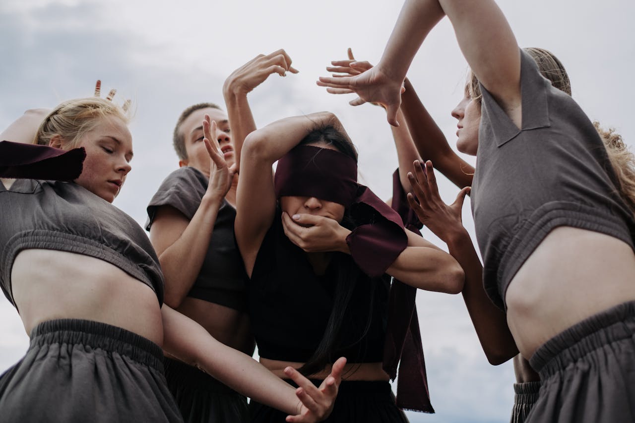 Conceptual dance scene with blindfolded women in gray dresses, creating an eerie and ritualistic atmosphere.