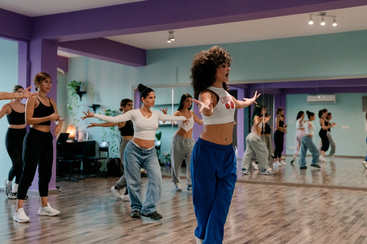 A group of adults participating in a lively dance class inside a modern studio.